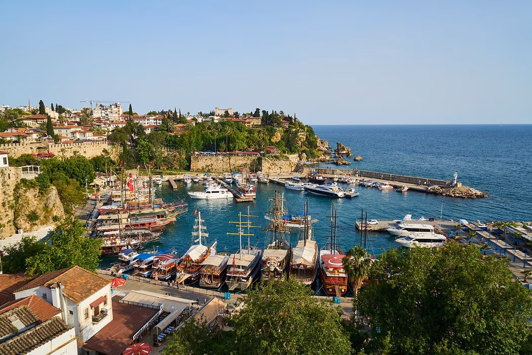 De oude haven van Antalya met boten aan de kade en de kliffen erachter