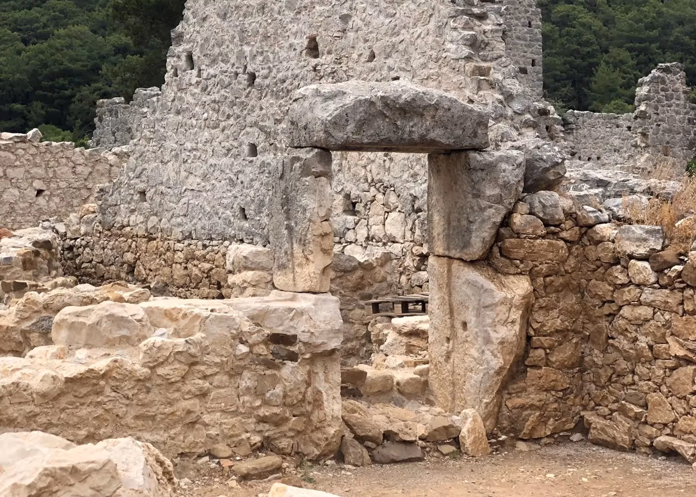 Begroeide stenen muur van een gebouw in de ruïnes van Olympos