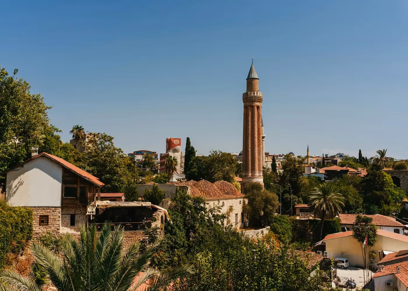 Rode bakstenen minaret met verticale ribbels, de Yivli Minare, boven de daken van de oude stad