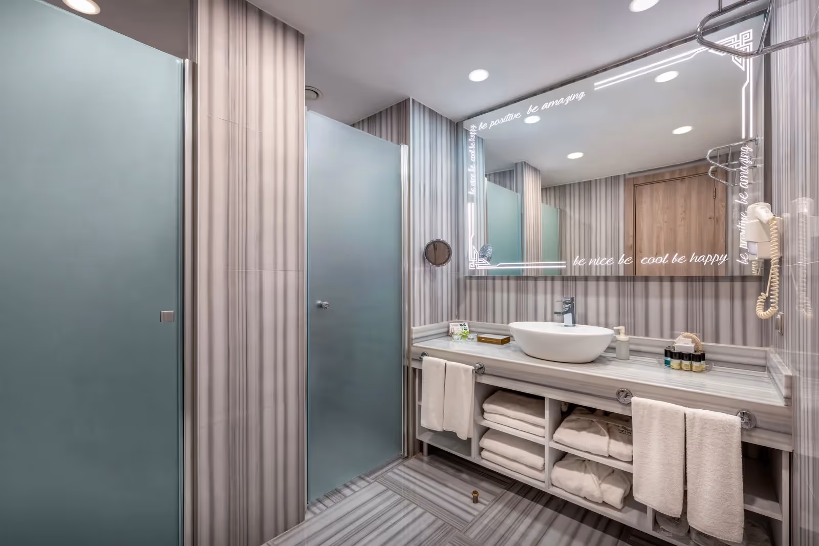 Badkamer met twee matglazen deuren, een wastafelmeubel en handdoeken in een familiekamer van Delphin BE Grand Resort in Lara