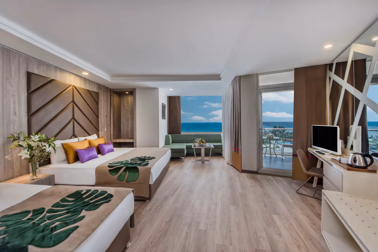 Be Large-kamer van Delphin BE Grand Resort met twee bedden, een bureau en een balkon met zeezicht