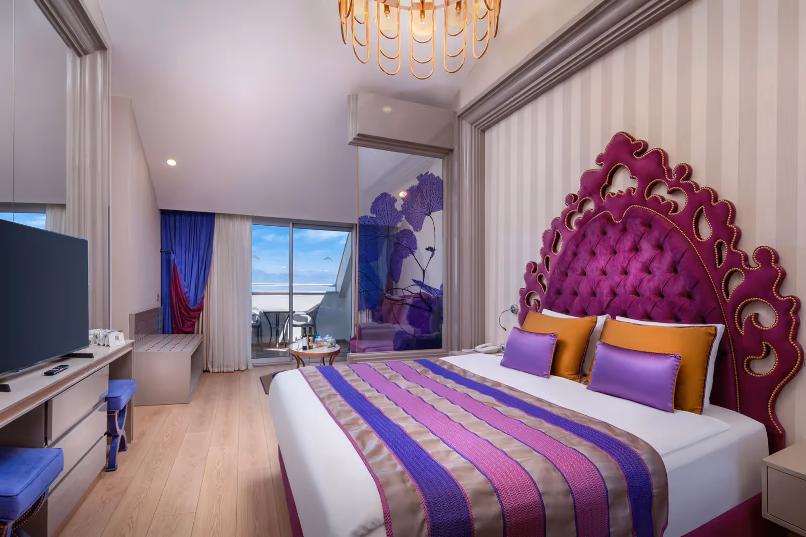 Kamer met tweepersoonsbed met een paars gecapitonneerd hoofdbord, een kroonluchter en een balkon in Delphin BE Grand Resort in Lara