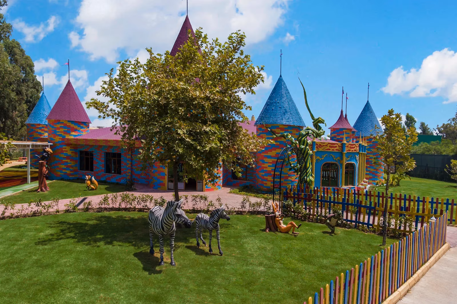 Kleurrijk sprookjeskasteel met torentjes en zebrabeelden op een grasveld bij Delphin Be Grand