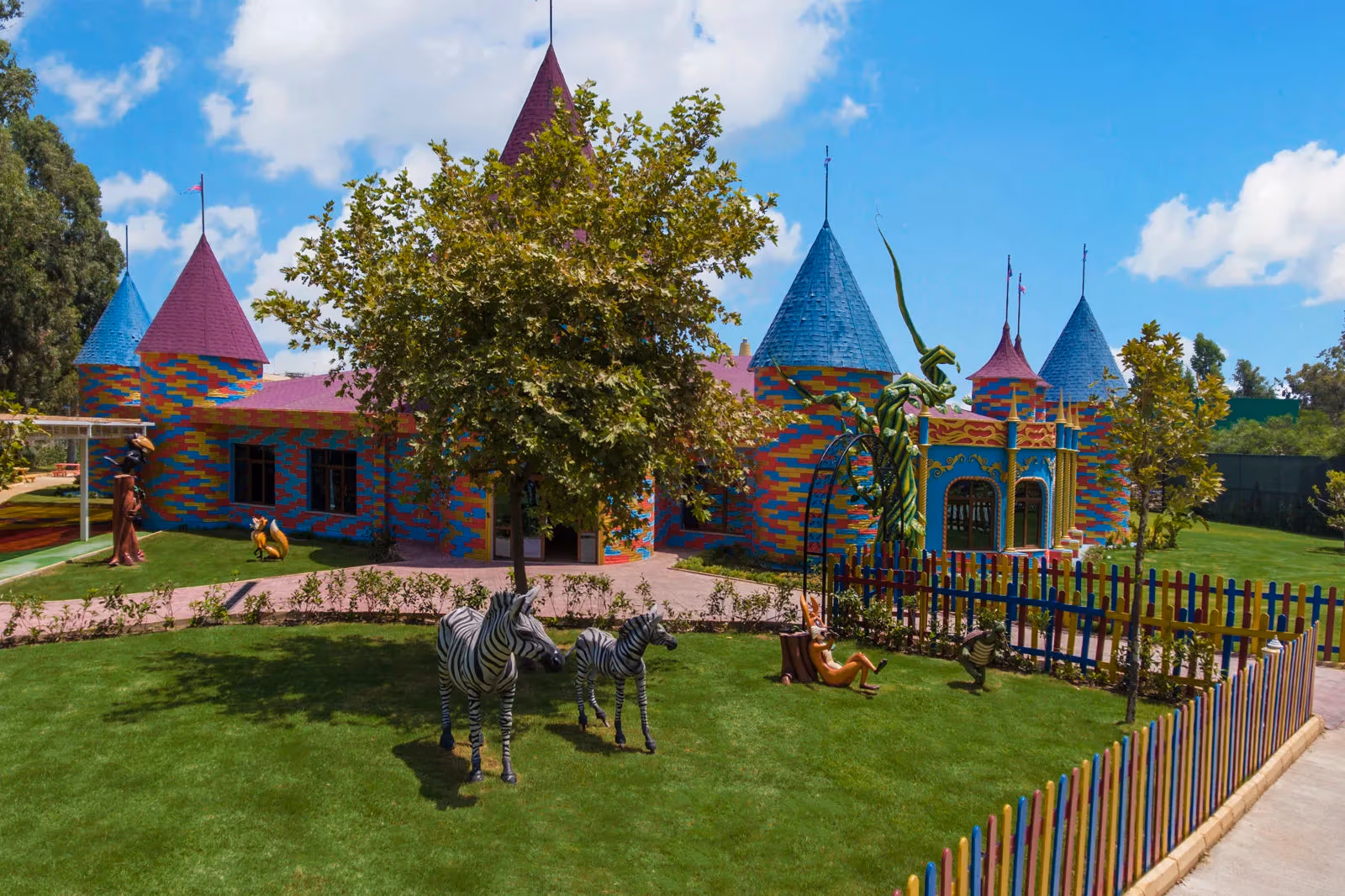 Kleurrijk sprookjeskasteel met torentjes en zebrabeelden op een grasveld bij Delphin BE Grand Resort in Lara