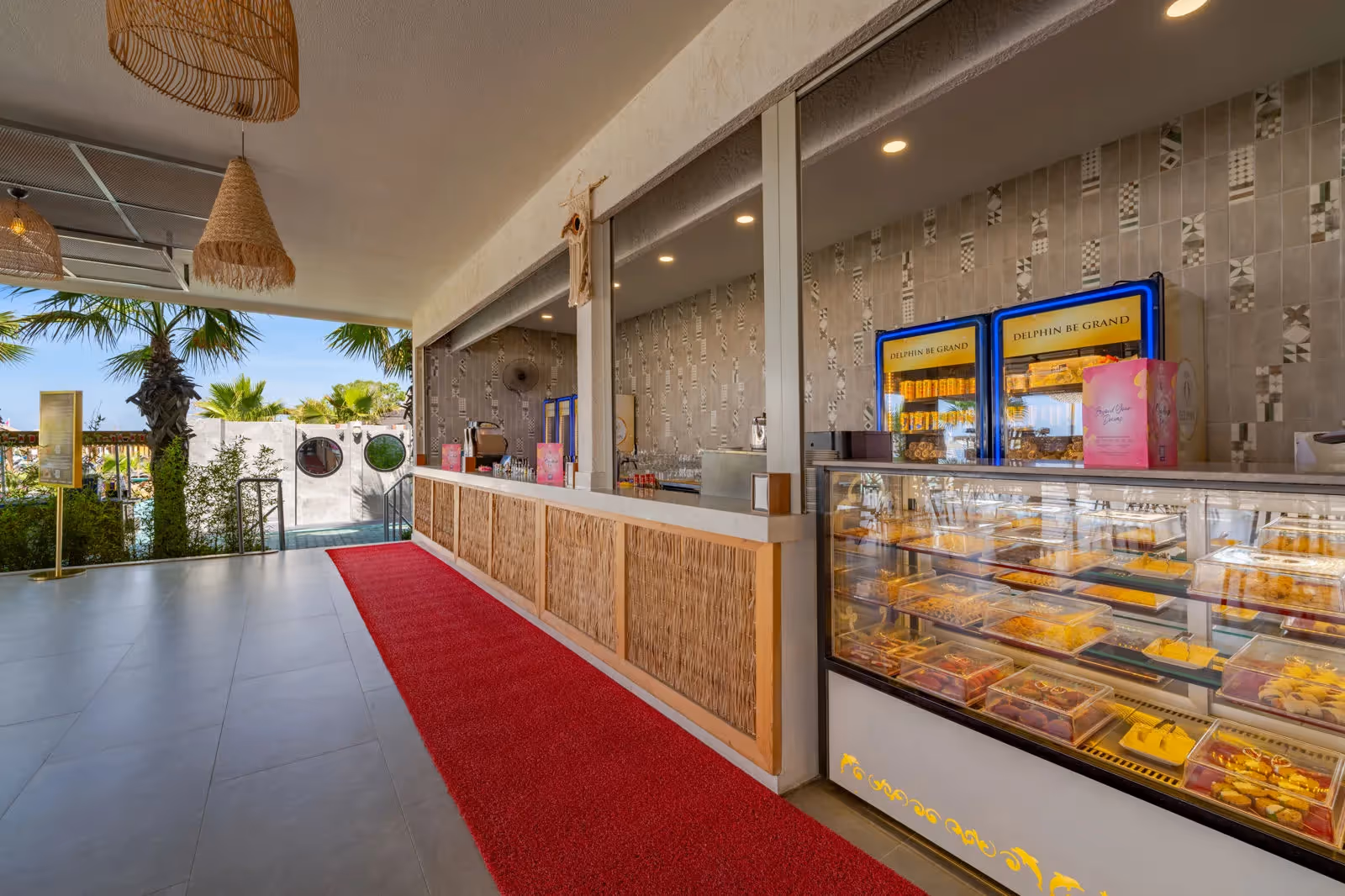 Patisseriebalie met een vitrine vol gebak en een rode loper in Delphin BE Grand Resort in Lara
