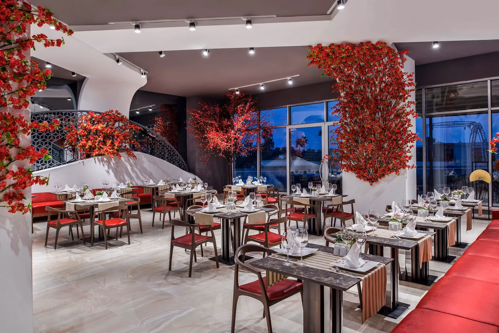 Restaurant van Delphin Be Grand met gedekte tafels, rode bloesemdecoratie en grote ramen
