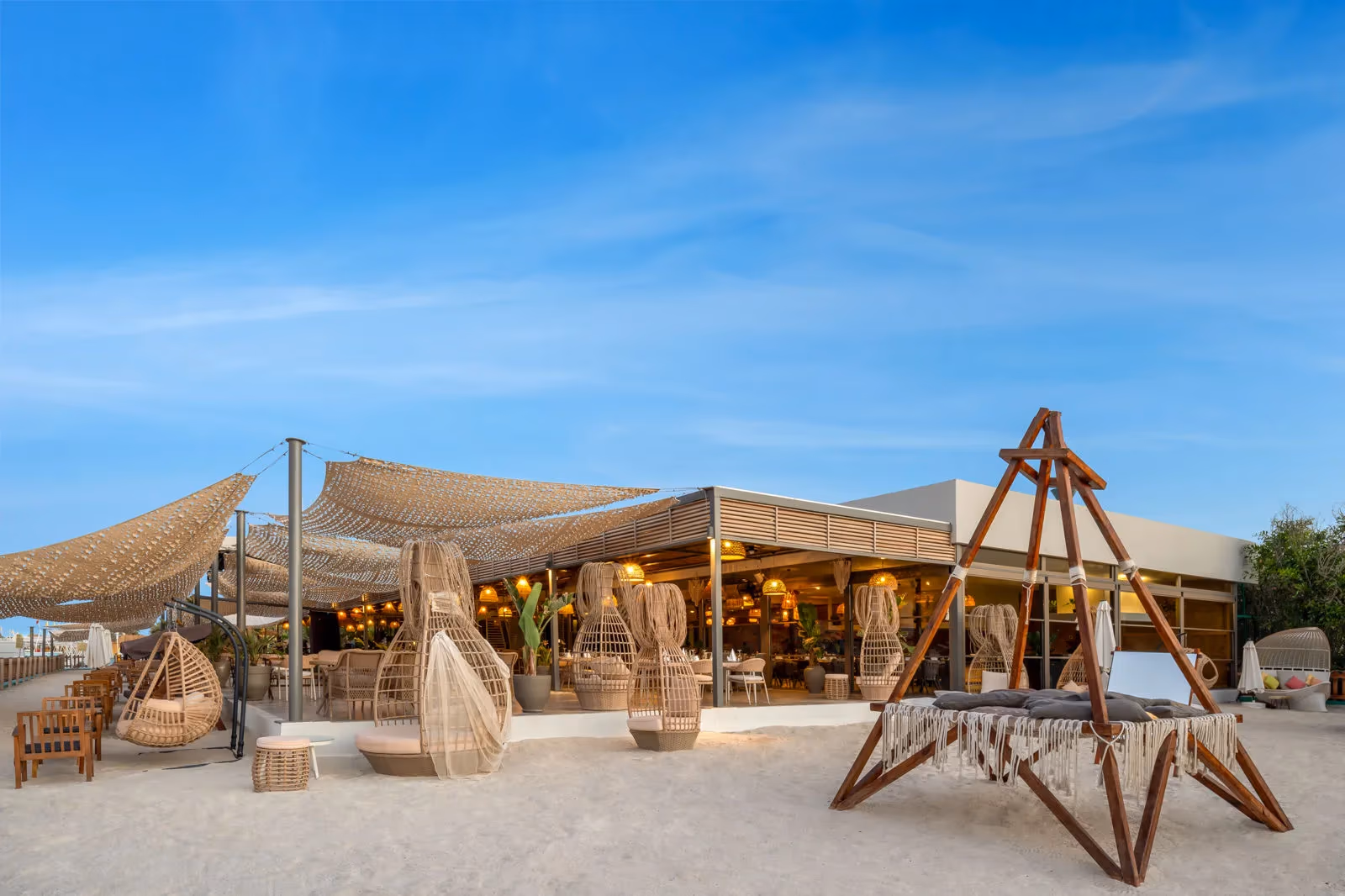 Loungeplek op het zand met hangstoelen, een houten schommel en schaduwdoeken bij Delphin BE Grand Resort in Lara
