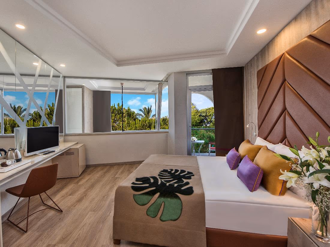 Kamer met tweepersoonsbed, een bureau en een raam met uitzicht op de tuin in Delphin BE Grand Resort in Lara