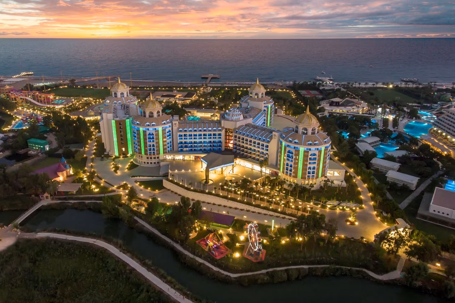 Luchtfoto van Delphin BE Grand Resort in Lara in de avond met verlichte gebouwen en tuinen