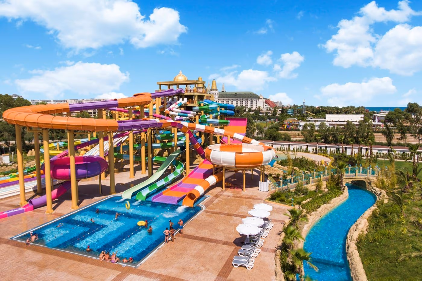Zwembad met gekleurde glijbanen en de lazy river ernaast bij Delphin BE Grand Resort in Lara