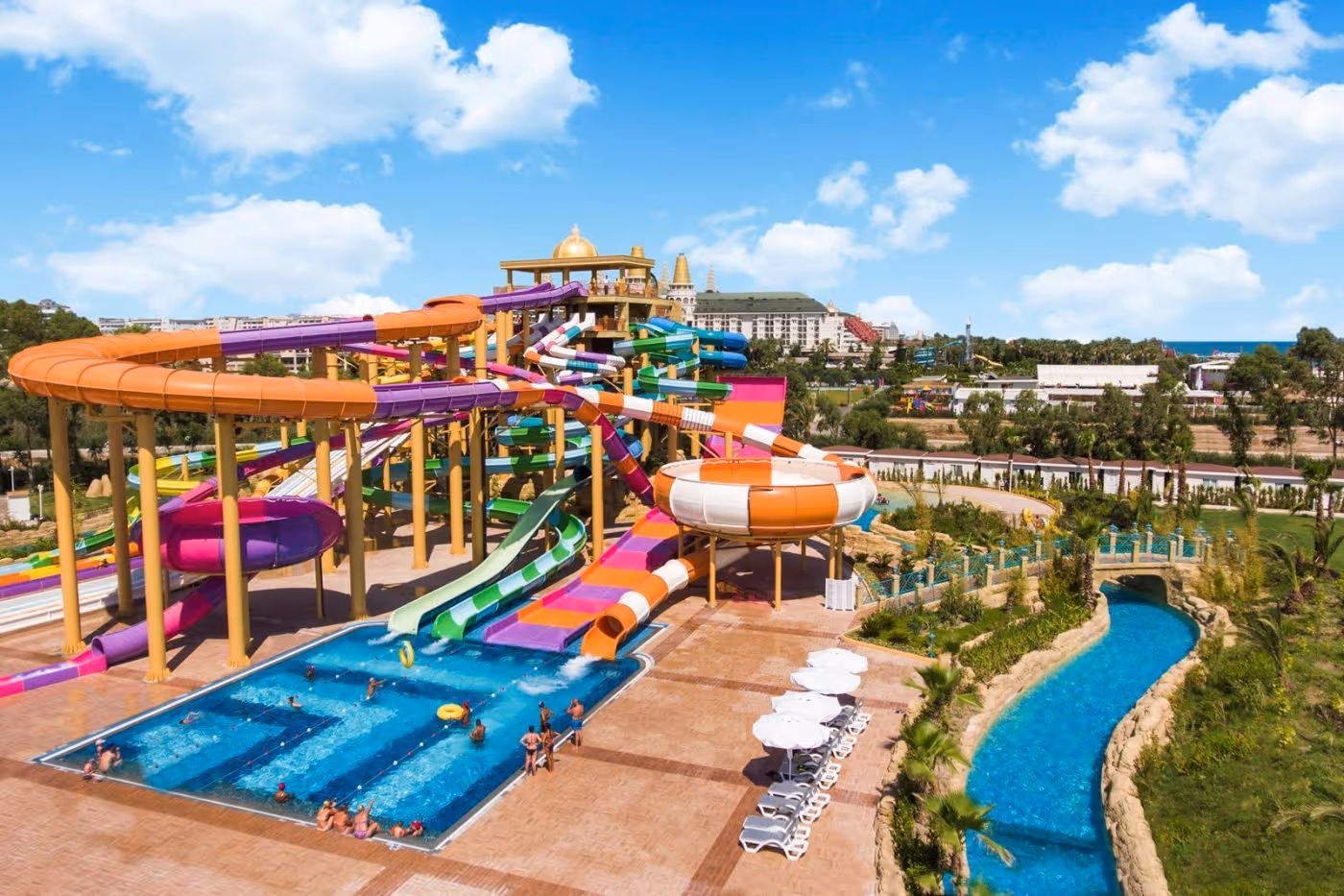 Zwembad met gekleurde glijbanen en de lazy river ernaast bij Delphin BE Grand Resort in Lara