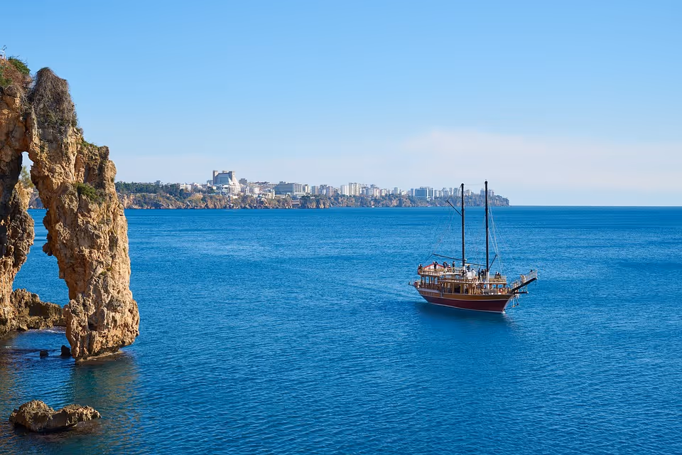 Rotsboog in zee met een houten zeilschip aan de Turkse kust