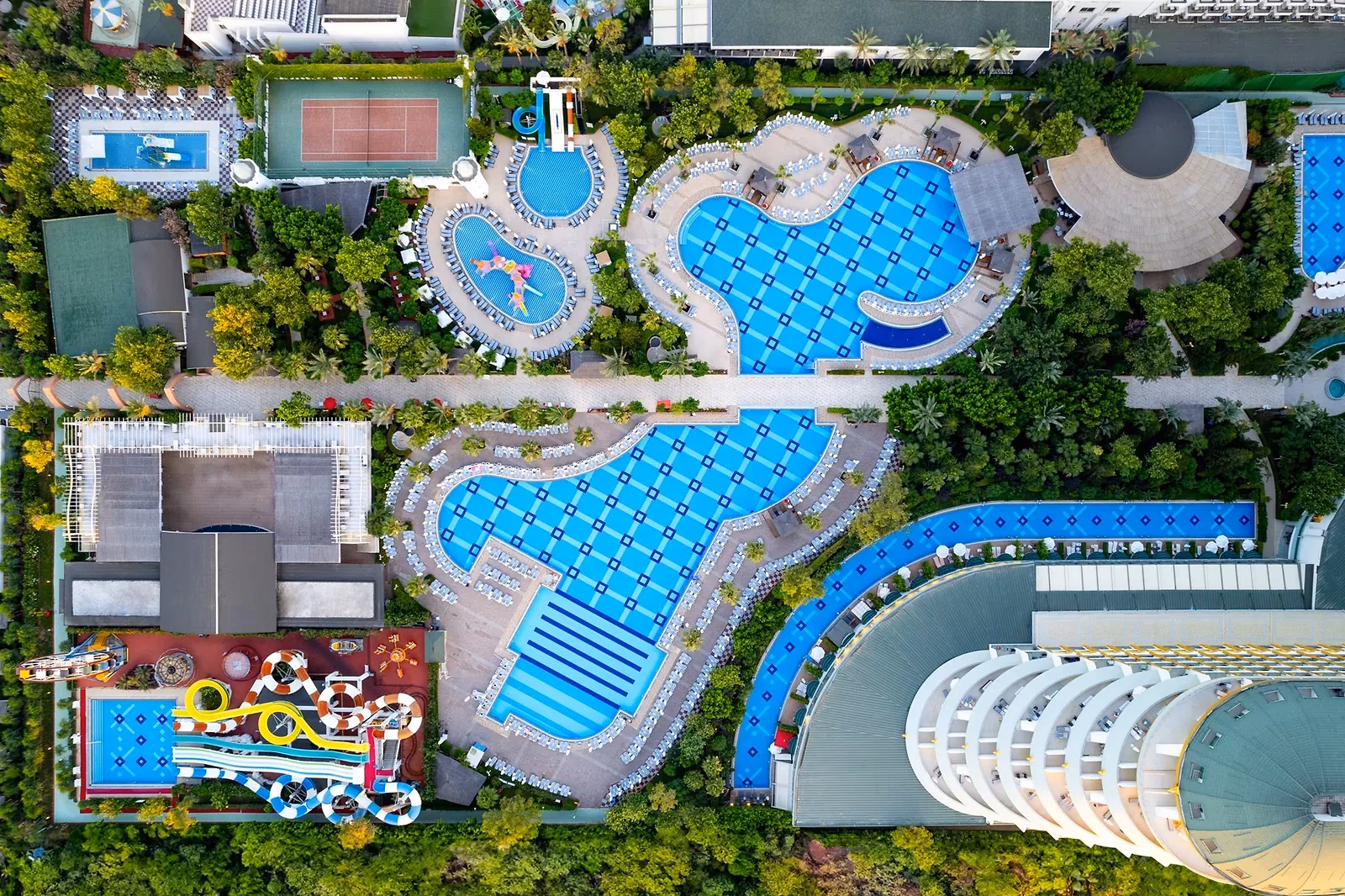 Luchtfoto recht van boven op de zwembaden, het glijbaanbad en het gebogen hoofdgebouw van Delphin Imperial in Lara