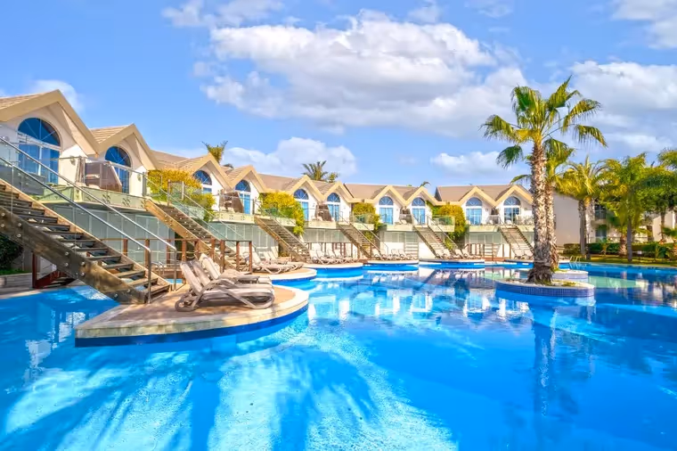 Zwembad met palmbomen en villa's bij Long Beach Resort in Türkler bij Alanya
